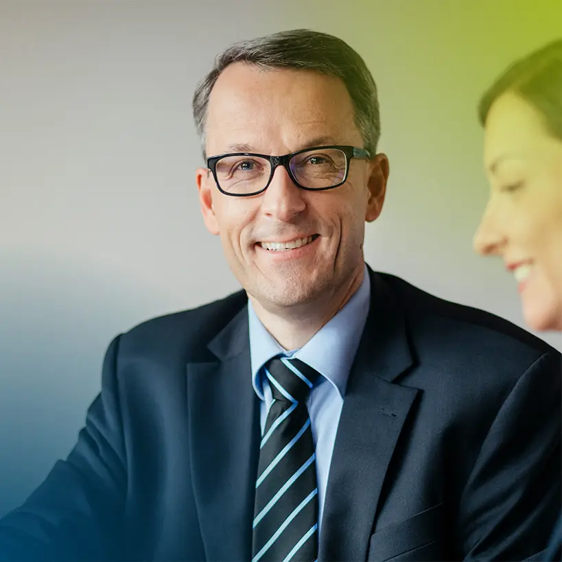 Thomas Jäger lächelt freundlich in die Kamera in einem modernen Büro. Als Diplom-Betriebswirt (FH) und Steuerberater in München bietet er umfassende Beratung und Unterstützung in der Steuerberatung an.