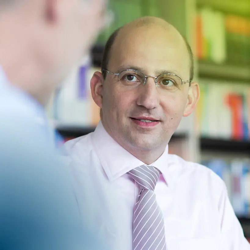 In einem modernen Büro lächelt Michael Siebel freundlich in die Kamera. Als Diplom-Kaufmann, Master of Arts (Wayne St. Univ.), Wirtschaftsprüfer und Steuerberater in München bietet er umfassende Beratungsleistungen in der Steuerberatung an.